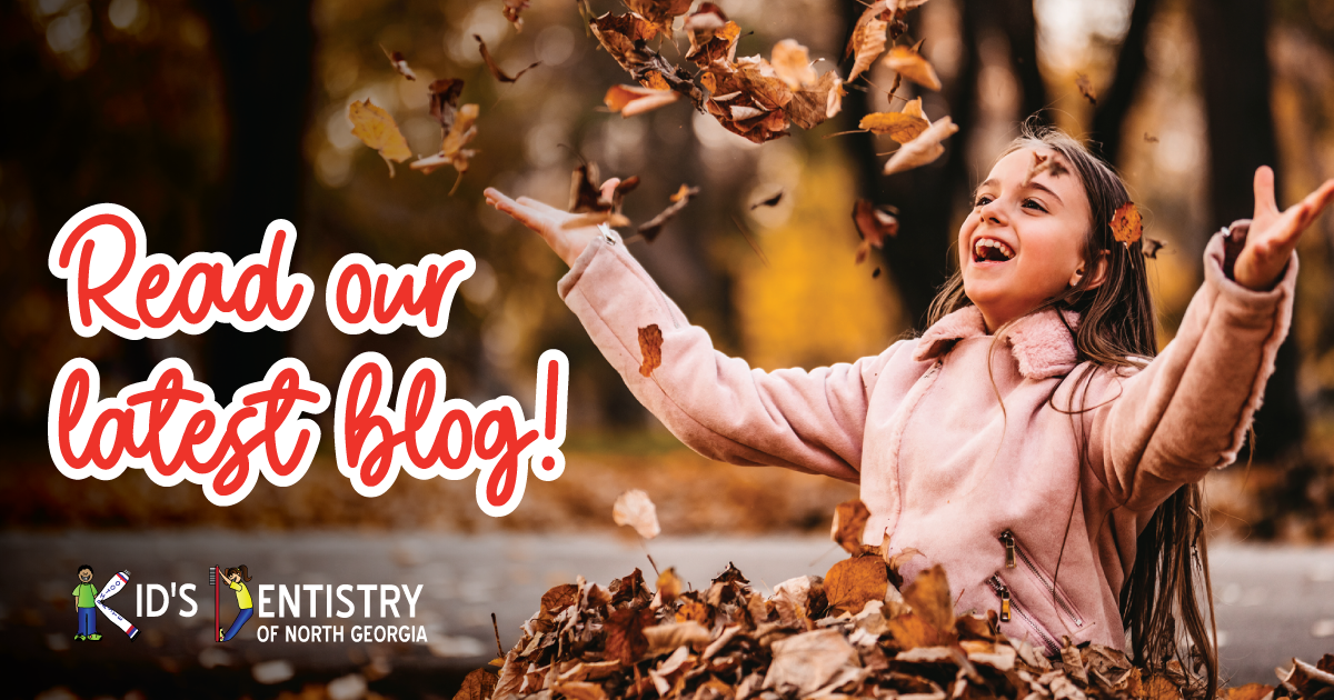 A young girl sits in a pile of leaves and throws them in the air. There is text superimposed on the image stating "Read our Latest Blog"
