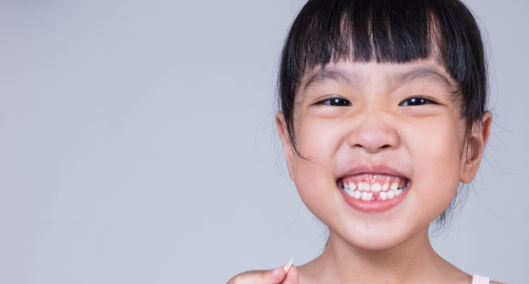 Asian Chinese little girl holding her missing tooth