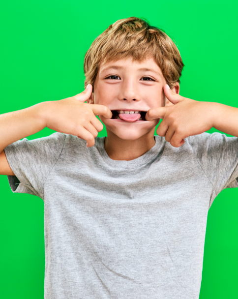 A blonde kid makes a silly face by pulling his mouth open at the sides and sticking his tongue out